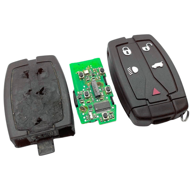 A broken land rover freelander 2 car key fob showing a worn black casing and exposed green circuit board and a repaired black 5 button key with car-related symbols.